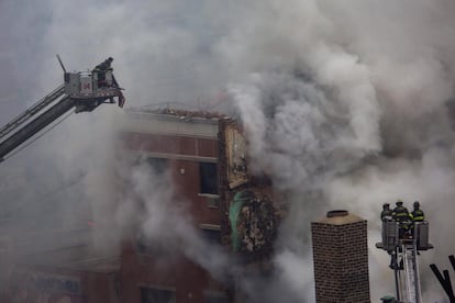 Grupos de bomberos trabajan en las labores de extinción desde las grúas de los camiones. La estructura de los edificios que han resistido la explosión asoman entre una intensa nube de humo provocada por el incendio.