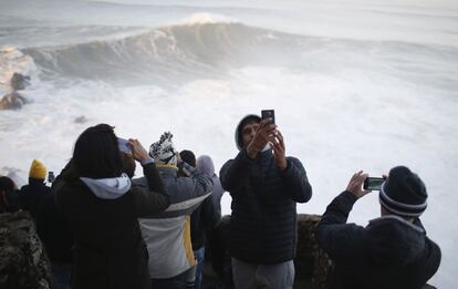 Un grupo de j&oacute;venes hace fotos con el m&oacute;vil a las olas que golpean contra las rocas en Nazar&eacute;. La afici&oacute;n a este deporte aumenta d&iacute;a a d&iacute;a en Portugal, que alberga una de las pruebas del principal circuito de surf en la localidad de Peniche, y Espa&ntilde;a, que hasta 2008 tambi&eacute;n reun&iacute;a a la &eacute;lite internacional en Mundaka, Vizcaya.