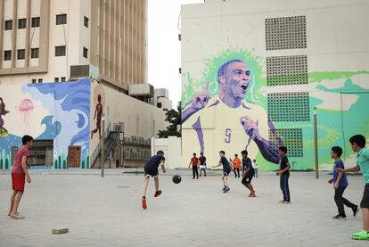 Un grupo de niños juega al fútbol frente a un mural dedicado a Ronaldo, este domingo en Doha (Qatar).