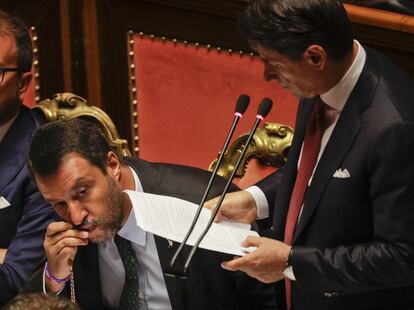 El primer ministro italiano, Giuseppe Conte, se dirige al Senado mientras el viceprimer ministro, Matteo Salvini, besa un rosario en el pleno de este martes, en Roma (Italia). Tras la moción de censura planteada por el líder de la ultraderechista Liga, Giuseppe Conte ha anunciado su dimisión, tildando de "irresponsable" a Salvini por desencadenar una crisis gubernamental que arriesga "una espiral de inestabilidad política y financiera".