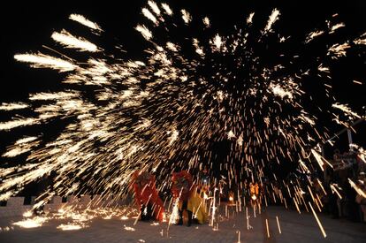 Unos bailarines realizan una danza del león bajo una lluvia de chispas de hierro fundido durante una actuación en Pinglu (China).