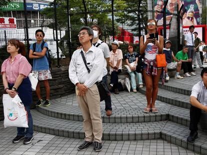 Algunos ciudadanos siguen el discurso del emperador en una plaza de Tokio.