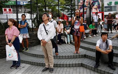 Algunos ciudadanos siguen el discurso del emperador en una plaza de Tokio.