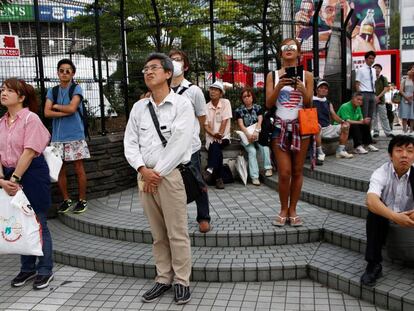 Algunos ciudadanos siguen el discurso del emperador en una plaza de Tokio.