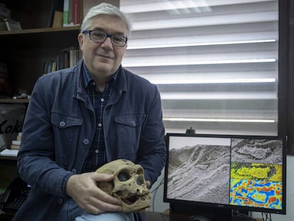 Fernando Muñiz, uno de los investigadores de las huellas de los neandertales, sostiene la reproducción de un cráneo de estos homínidos mientras muestra la huella hallada en Gibraltar.
 