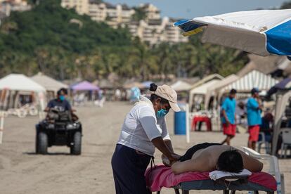 Una mujer da un masaje a un turista de la playa Revolcadero en Acapulco. La zona busca ahora recuperar el glamur turístico del que gozó en el pasado.