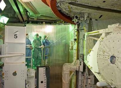 Miembros de la tripulación observan la carga para la misión en la bodega del <i>Atlantis</i>.