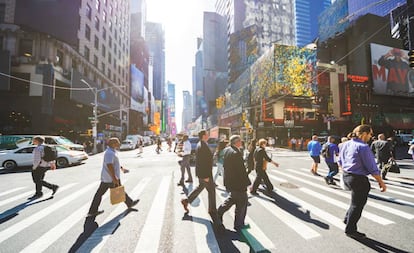 Varias personas cruzan la Séptima Avenida de Nueva York.