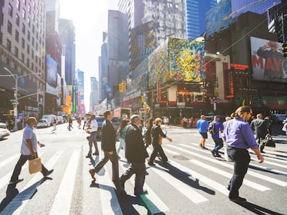 Varias personas cruzan la Séptima Avenida de Nueva York.