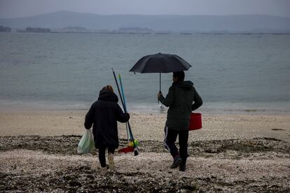 Dos voluntarios acudían a retirar 'pellets' en Illa de Arousa, Pontevedra, el lunes.