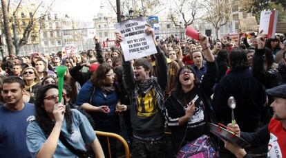 Un estudiante exhibe una pancarta en inglés que reza: "No podemos permitirnos una educación pública, pero nos encanta quemar dinero público".