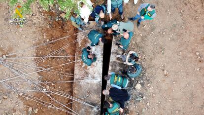 Varios guardias revisan una cueva cubierta con una losa enorme, sita en la finca donde han sido hallados los huesos.