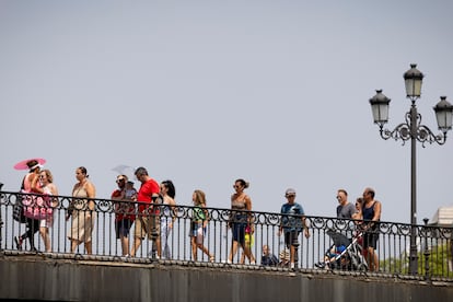 Paseantes se protegen del calor este sábado en el puente de Triana, en Sevilla. FOTO: PACO PUENTES (EL PAÍS)