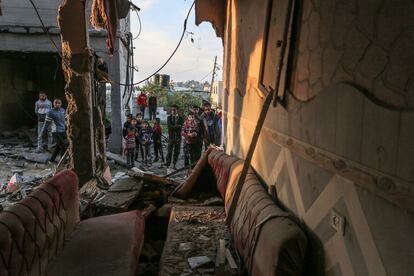 Un grupo de palestinos mira los restos de una casa destruida en un bombardeo en Rafah, este domingo.