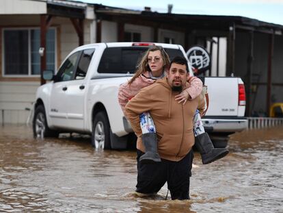 Ryan Orosco, of Brentwood, carries his wife Amanda Orosco, from their flooded home on Bixler Road in Brentwood, Calif., on Monday, Jan. 16, 2023.
