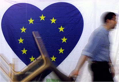 Un empleado del Parlamento Europeo arrastra un carrito con muebles, mientras pasa con un corazón con el color azul de la UE y las estrellas.