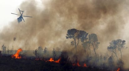 Un helic&oacute;ptero sobrevuela este lunes el fuego durante los trabajos de extinci&oacute;n en los alrededores de Alcublas y Liria.