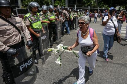 Una mujer de la oposición se enfrenta a la policía antidisturbios con unas flores, el 6 de mayo de 2017 en Caracas.