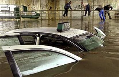 Un taxi quedó atrapado en un túnel subterráneo de Sevilla.
Dos peatones, ayer, en una calle del barrio sevillano de Los Remedios.