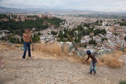 Dos jóvenes juegan en el lugar de Granada previsto para la construcción de un mirador  y donde habitan algunos vecinos en casas cueva.
