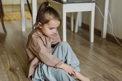 Una niña se sienta en el suelo, incómoda con su ropa.