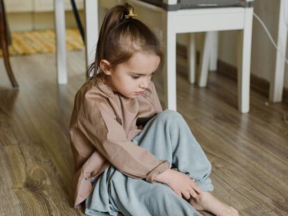 Una niña se sienta en el suelo, incómoda con su ropa.