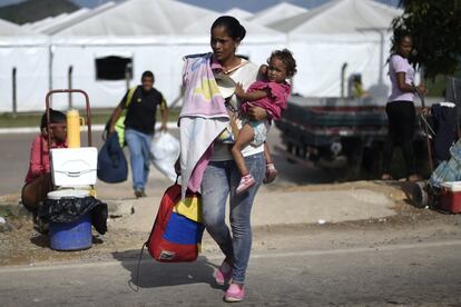 Uma mulher segura a filha nos braços enquanto atravessa a fronteira entre a Venezuela e o Brasil em 23 de agosto de 2018. A diáspora dos venezuelanos está prestes a se configurar na maior da América Latina nos últimos 50 anos. De acordo com dados da ONU, mais de três milhões de pessoas deixaram o país nos últimos anos e estima-se que a cifra aumente para mais de cinco milhões até o final de 2019. A Venezuela é um país onde 5.000 pessoas diariamente recolhem seus pertences para escapar do colapso econômico e da crise humanitária que assolam a nação. Somente para a Espanha emigraram mais de 200.000 pessoas, de acordo com dados da Organização Internacional para as Migrações, órgão das Nações Unidas, em 2018, sem contar aqueles em situação irregular ou venezuelanos de nacionalidade europeia.