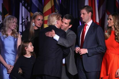Donald Trump es abrazado por su hijo Donald Trump Jr. rodeado por su familia dtras conocer los resultados electorales, en Nueva York.