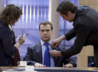 Una maquilladora y un asistente dan los últimos retoques al presidente ruso, Dmitri Medvédev, antes de participar en una entrevista televisiva con los directores de tres canales de cobertura nacional