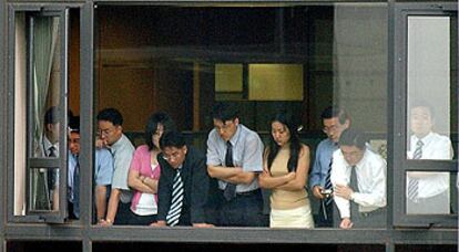 Un grupo de empleados de Hyundai mira por la ventana desde la que se lanzó Chung Mong Hun, responsable del grupo coreano.