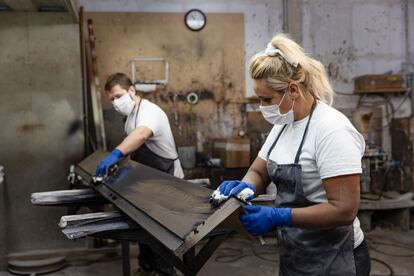 Dos trabajadores con mascarilla en su taller.