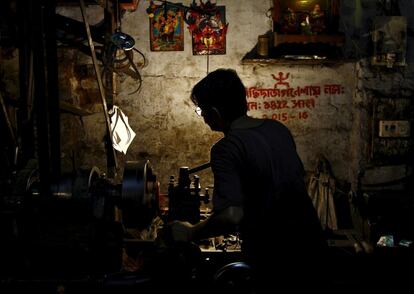 Un trabajador maneja un torno en el que hace piezas para coches en una pequeña fábrica de Calcuta (India).