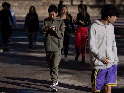 Un alumno de secundaria usando el teléfono móvil durante el recreo del instituto.