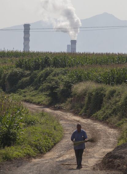 El humo sale de la chimenea de una fábrica de acero al lado de un campo de maíz en una mañana brumosa y contaminada en la ciudad Han Dan, provincia de He Bei, en China. 