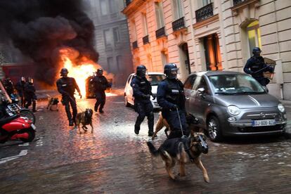 Agentes de la policía, junto a sus perros, corren por una calle céntrica de París durante los enfrentamientos con un grupo de 'chalecos amarillos' este sábado.