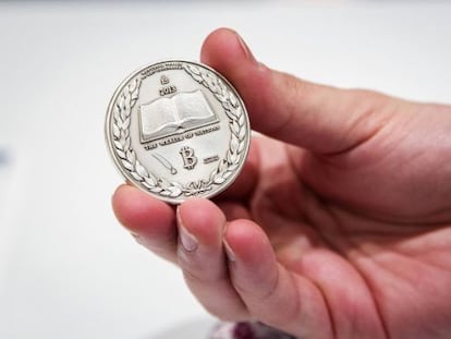 Un hombre sostiene una maqueta de bitcoin.