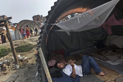 A Nepalese man, whose house was damaged in the April 25 earthquake, plays a flute in a temporary shelter made out of galvanized sheet in Bhaktapur, Nepal, Tuesday, May 19, 2015. Nepal is facing billions in reconstruction costs with almost 745,600 buildings and homes damaged or destroyed, including at least 87,700 in the capital, according to Nepal’s emergency authority. (AP Photo/Niranjan Shrestha)