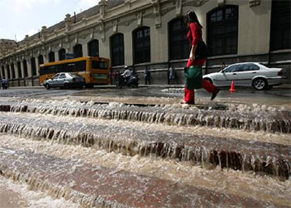 Una mujer camina junto a las escaleras de la plaza de toros de Valencia, inundadas de agua por la rotura de la tubería, ayer.