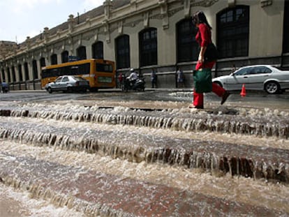 Una mujer camina junto a las escaleras de la plaza de toros de Valencia, inundadas de agua por la rotura de la tubería, ayer.