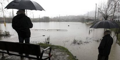 Vecinos de Hernani, observan el campo de rugby Landare, anegado por el desbordamiento del río Urumea.