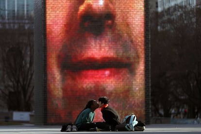 La estudiante del Columbia College Chicago Najah Muhammad, a la izquierda, y Eli Herrera se besan mientras disfrutan del buen tiempo en el Millennium Park de Chicago.