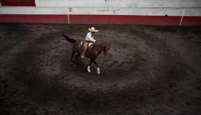 Un charro prepara a su caballo minutos antes de participar en una competici&oacute;n.