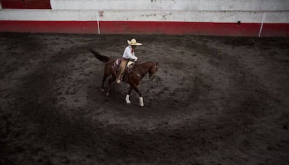 Un charro prepara a su caballo minutos antes de participar en una competición.