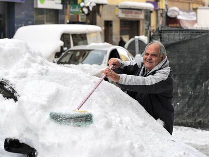 Un hombre trata de limpiar su coche, cubierto de nieve, ayer en Vitoria.