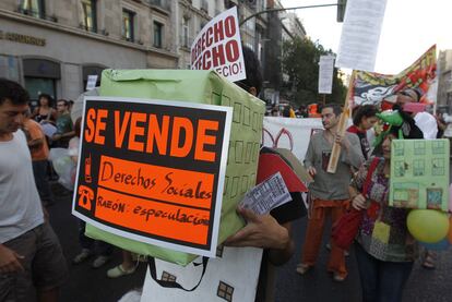 Una participantes en la marcha de Madrid muestra un cartel con el lema: "Se venden derechos sociales. Razón: especulación".