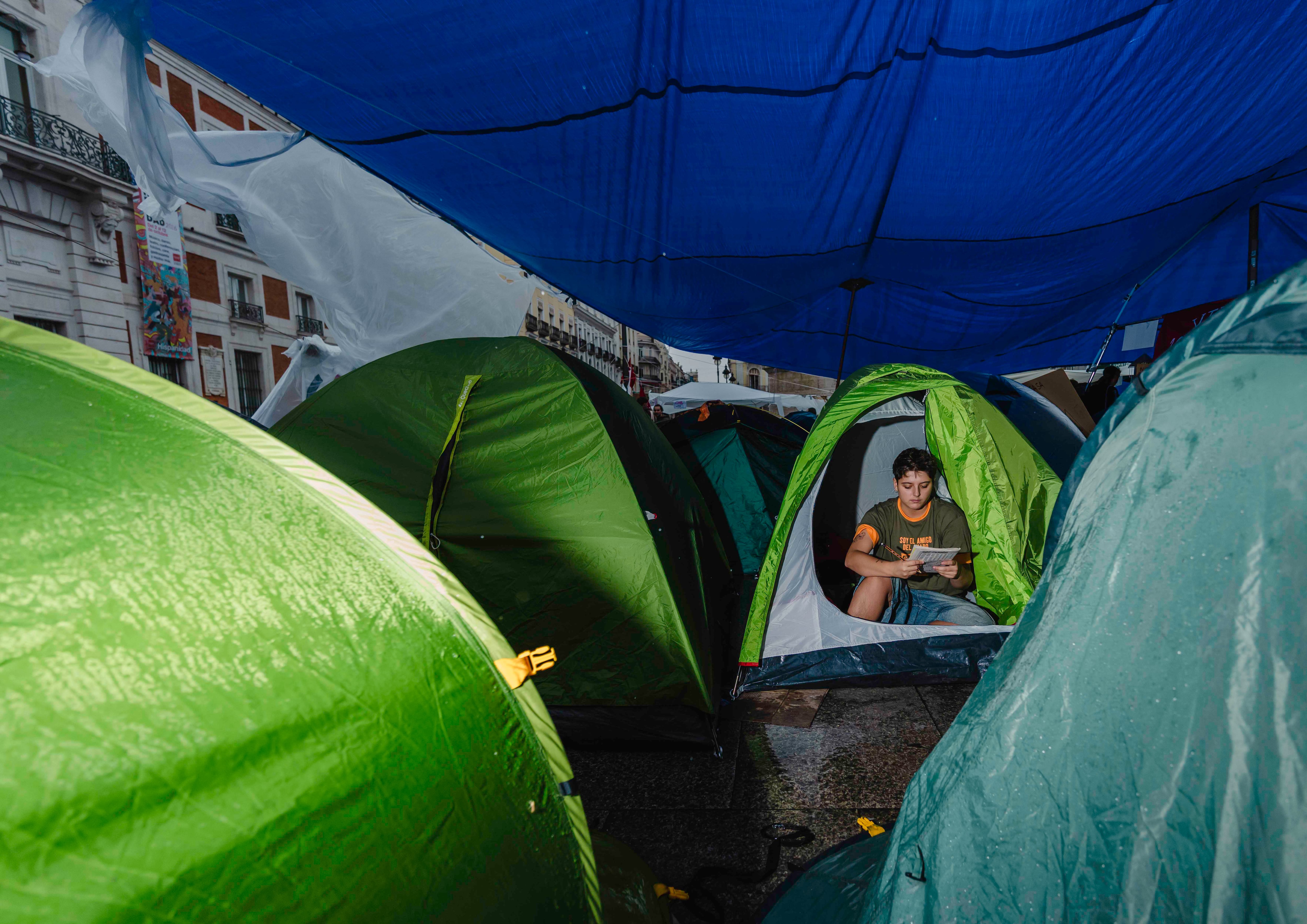 Un manifestante acampado en la Puerta del Sol lee en una tienda de campaña, este lunes.
