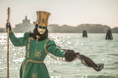 Una persona con un tradicional disfraz verde y una máscara posa cerca del Gran Canal, en Venecia (Italia).