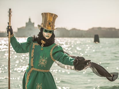Una persona con un tradicional disfraz verde y una máscara posa cerca del Gran Canal, en Venecia (Italia).