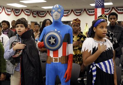 Yassin Elalamy, de Egipto, izquierda, Esdras Dessie, de Etiopía, y Hilary Suárez, de la República Dominicana, recitan el juramento a la bandera durante una ceremonia de naturalización con temática de Halloween, en Baltimore.