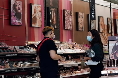 A worker, at left, tends to a customer at a cosmetics shop on Thursday, May 20, 2021